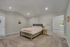 Primary bedroom with vaulted ceiling, and view into bonus room