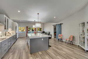 Kitchen with sink, pendant lighting, a barn door, white cabinets, and gray cabinets