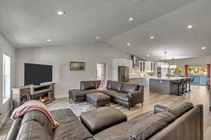 Living room with sink, light hardwood / wood-style flooring, and vaulted ceiling