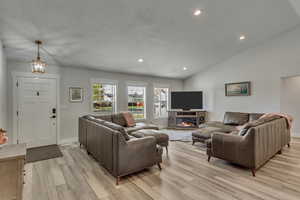 Living room featuring a textured ceiling, vaulted ceiling, and light wood-type flooring