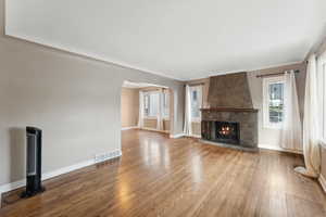 Unfurnished living room with a large fireplace, hardwood / wood-style flooring, and plenty of natural light