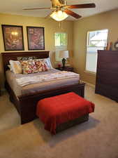 Carpeted bedroom with multiple windows and ceiling fan