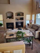 Carpeted living room with a towering ceiling