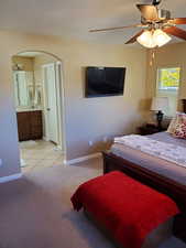 Carpeted bedroom with ensuite bathroom and ceiling fan