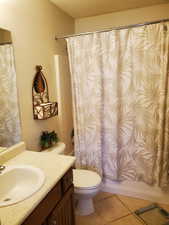 Full bathroom featuring tile patterned flooring, shower / bath combination with curtain, toilet, and vanity