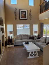 Carpeted living room with a towering ceiling