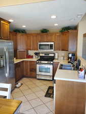 Kitchen featuring sink, light tile patterned floors, and appliances with stainless steel finishes