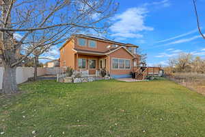 Rear view of property featuring a lawn, solar panels, and a deck