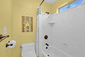 Bathroom with shower / bath combination with curtain and toilet