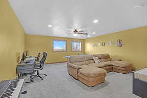 Living room featuring a textured ceiling, carpet floors, and ceiling fan