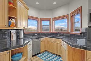 Kitchen featuring light brown cabinets, sink, light hardwood / wood-style flooring, appliances with stainless steel finishes, and tasteful backsplash