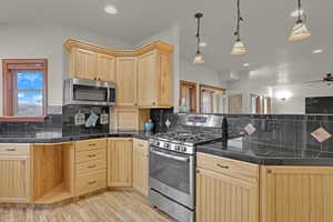 Kitchen with a wealth of natural light, light brown cabinets, hanging light fixtures, kitchen peninsula, and appliances with stainless steel finishes