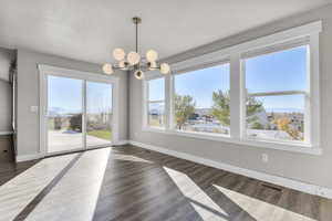 Unfurnished dining area with dark wood-type flooring, a textured ceiling, a notable chandelier, and a mountain view