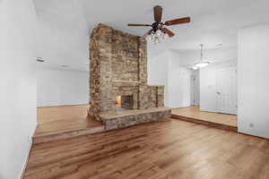 Unfurnished living room with a multi sided fireplace, a textured ceiling, hardwood / wood-style flooring, and ceiling fan