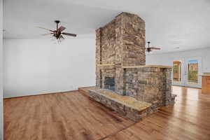 Unfurnished living room with a fireplace, a textured ceiling, light hardwood / wood-style floors, and vaulted ceiling