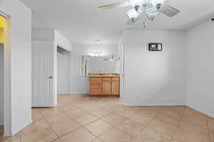 Bathroom featuring tile patterned floors, ceiling fan, vanity, and a textured ceiling