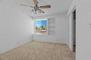 Unfurnished bedroom with ceiling fan, carpet floors, a textured ceiling, and a closet