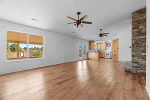 Unfurnished living room featuring sink, light hardwood / wood-style floors, and a textured ceiling