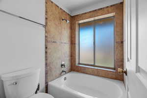 Bathroom with tiled shower / bath combo and toilet