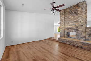 Unfurnished living room featuring a multi sided fireplace, a textured ceiling, and hardwood / wood-style flooring