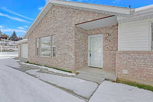 Snow covered property entrance with a garage