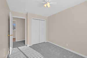 Unfurnished bedroom with ceiling fan, light colored carpet, and a closet