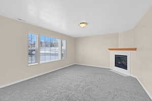 Unfurnished living room featuring carpet flooring and a textured ceiling