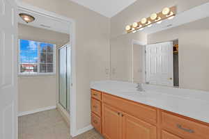 Bathroom featuring tile patterned flooring, vanity, and a shower with shower door