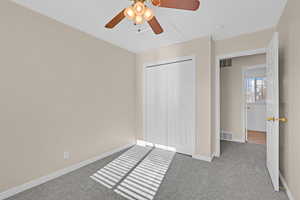 Unfurnished bedroom featuring ceiling fan, light carpet, and a closet