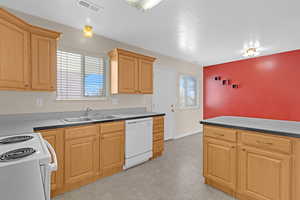 Kitchen with a textured ceiling, white appliances, sink, and light brown cabinetry