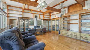 Living room with a wood stove, plenty of natural light, a towering ceiling, and light hardwood / wood-style floors