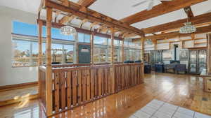 Sunroom / solarium featuring beam ceiling, ceiling fan with notable chandelier, and a wood stove