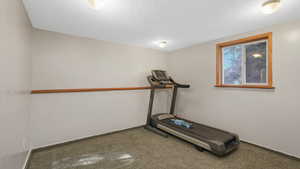 Workout area with carpet flooring and a textured ceiling