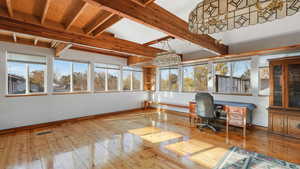 Office area featuring a notable chandelier, vaulted ceiling with beams, and light wood-type flooring