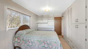 Bedroom with light carpet, a closet, and a textured ceiling