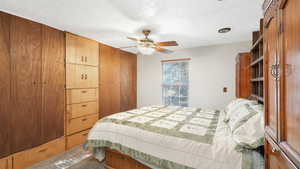 Carpeted bedroom featuring ceiling fan, a closet, and a textured ceiling