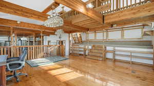 Misc room with hardwood / wood-style flooring, a notable chandelier, and a high ceiling