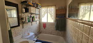 Bathroom with a bathing tub, toilet, and tile walls