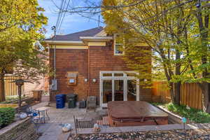 Back of house with a covered hot tub and a patio area