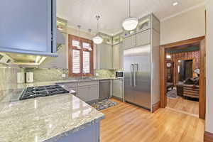 Kitchen featuring pendant lighting, sink, appliances with stainless steel finishes, tasteful backsplash, and light hardwood / wood-style floors