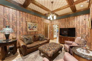 Living room with beamed ceiling, ornamental molding, an inviting chandelier, and coffered ceiling