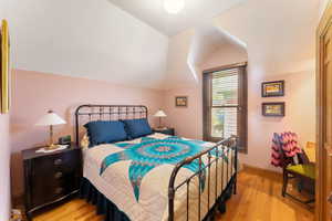 Bedroom with light wood-type flooring and lofted ceiling