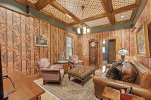 Living room featuring beam ceiling, a chandelier, coffered ceiling, and light wood-type flooring