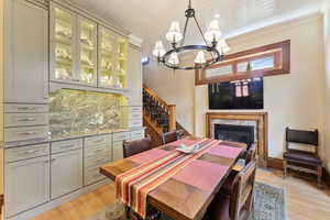 Dining room featuring a high end fireplace, crown molding, light hardwood / wood-style flooring, wooden ceiling, and a chandelier