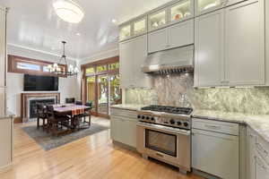 Kitchen with light hardwood / wood-style floors, light stone countertops, and stainless steel range