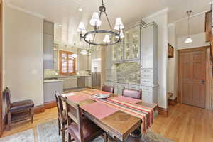 Dining room featuring a notable chandelier, crown molding, light wood-type flooring, and sink