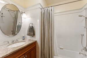 Bathroom with shower / bath combination with curtain, vanity, and tasteful backsplash