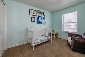 Bedroom featuring carpet flooring, a closet, and a nursery area