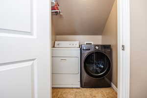 Laundry area featuring light tile patterned floors and washing machine and clothes dryer