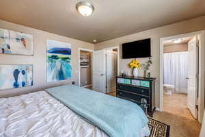 Bedroom with ensuite bathroom and light colored carpet